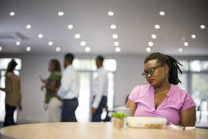 Young woman sits alone while coworkers go out to lunch together